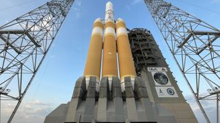 a white and orange rocket stands upright on a launch pad