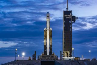 A SpaceX Falcon Heavy rocket on the launch pad with clouds in the background for the X-37B OTV-7 mission